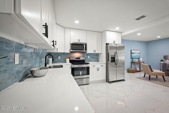 kitchen with sink, backsplash, stainless steel appliances, and white cabinets