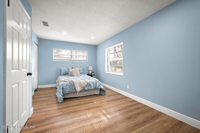 bedroom with light hardwood / wood-style floors and a textured ceiling