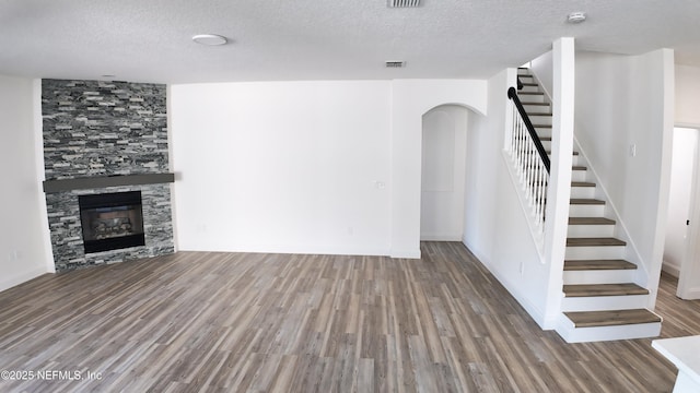 unfurnished living room with hardwood / wood-style floors, a fireplace, and a textured ceiling