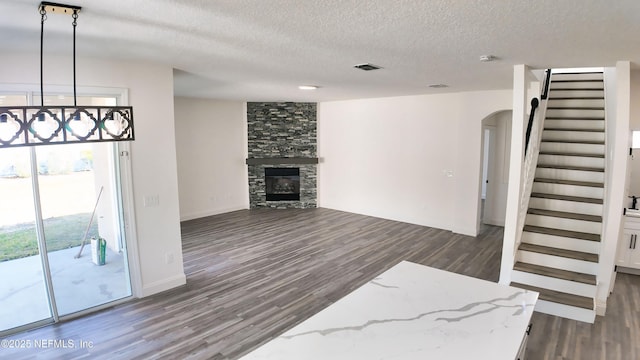 living room with dark wood-type flooring, a fireplace, and a textured ceiling