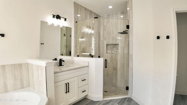 bathroom with hardwood / wood-style flooring, vanity, shower with separate bathtub, and a textured ceiling