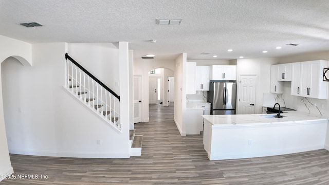 kitchen featuring sink, stainless steel fridge, kitchen peninsula, and white cabinets