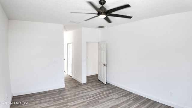 empty room with ceiling fan, light hardwood / wood-style floors, and a textured ceiling