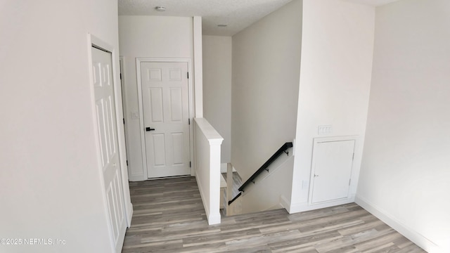 staircase with wood-type flooring and a textured ceiling