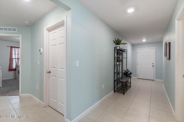 hallway featuring light tile patterned floors and a textured ceiling