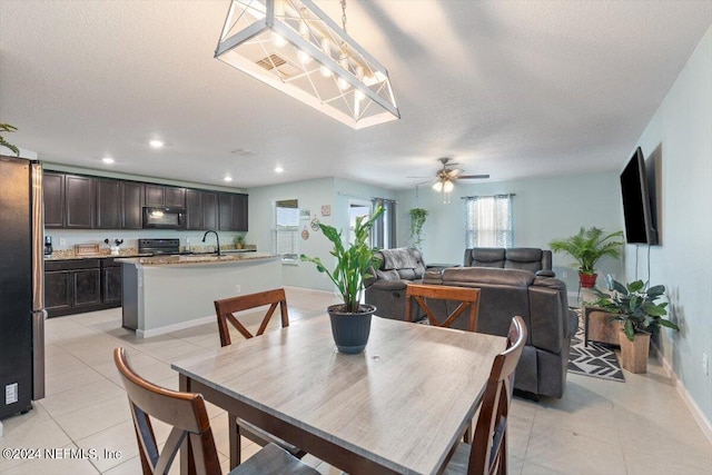 dining room with ceiling fan, sink, a textured ceiling, and light tile patterned floors