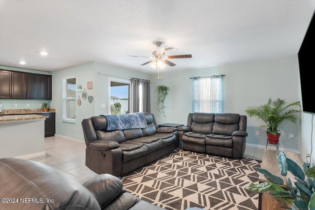 tiled living room featuring ceiling fan, plenty of natural light, and a textured ceiling