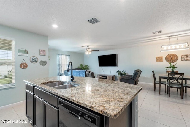 kitchen featuring an island with sink, black dishwasher, sink, light stone countertops, and a textured ceiling