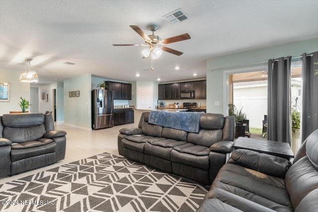 living room with ceiling fan, a textured ceiling, and light tile patterned floors