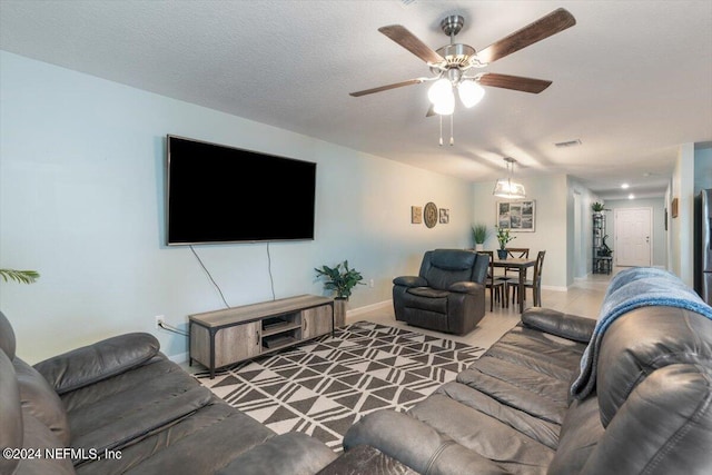 living room featuring ceiling fan and a textured ceiling