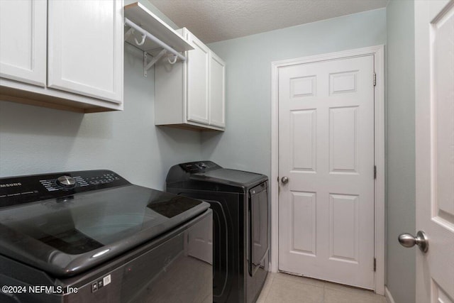 clothes washing area featuring cabinets, independent washer and dryer, a textured ceiling, and light tile patterned flooring