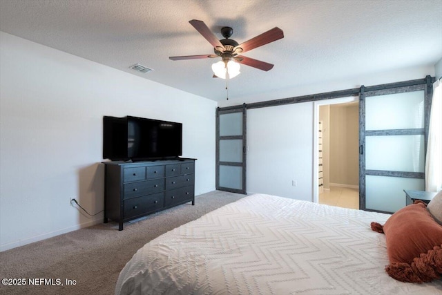 bedroom featuring ceiling fan, light colored carpet, a barn door, and a textured ceiling