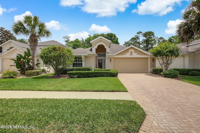 view of front of house featuring a front yard, decorative driveway, an attached garage, and stucco siding