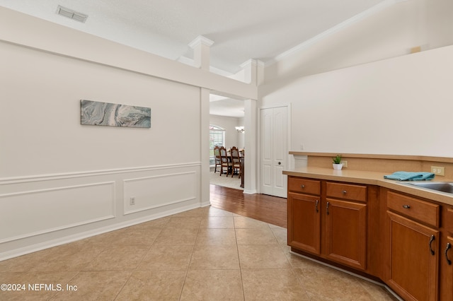 kitchen featuring ornamental molding, lofted ceiling, and light tile patterned floors