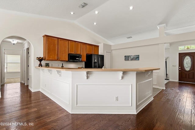 kitchen with lofted ceiling, a breakfast bar area, dark hardwood / wood-style floors, a wealth of natural light, and black appliances