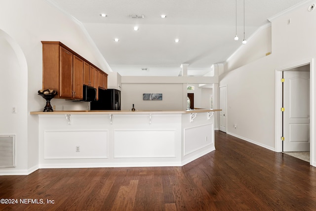 kitchen with lofted ceiling, a breakfast bar, black appliances, dark hardwood / wood-style flooring, and kitchen peninsula