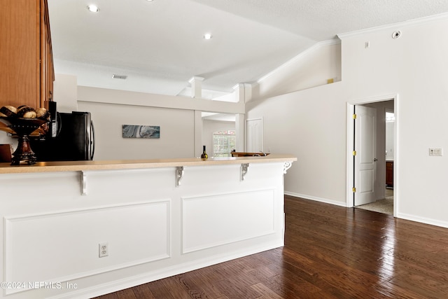 kitchen featuring lofted ceiling, stainless steel refrigerator, a kitchen breakfast bar, dark hardwood / wood-style floors, and kitchen peninsula