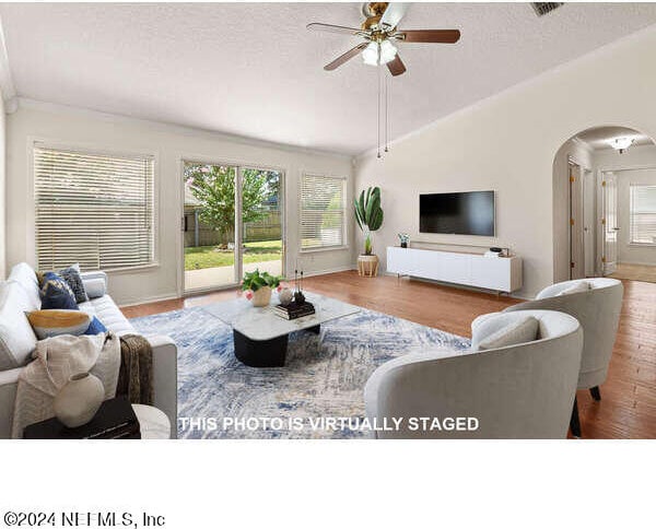 living room with ceiling fan, wood-type flooring, vaulted ceiling, and a wealth of natural light