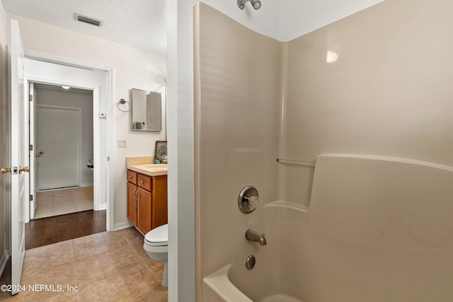 full bathroom featuring vanity, toilet, bathing tub / shower combination, tile patterned floors, and a textured ceiling