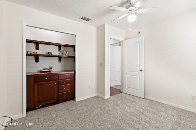 unfurnished bedroom featuring ceiling fan, light colored carpet, and a textured ceiling