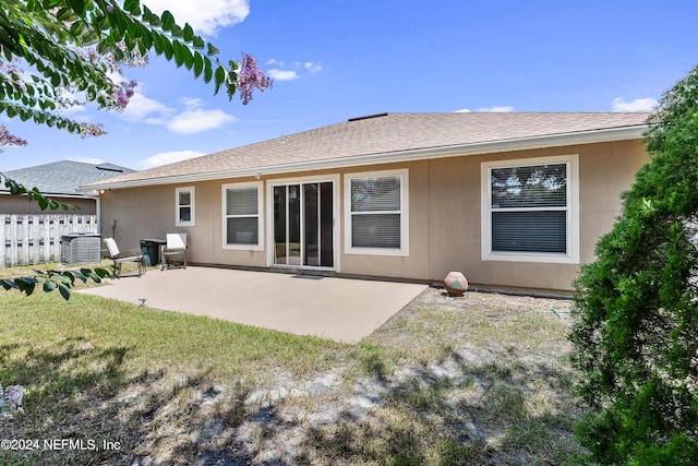 rear view of house featuring cooling unit, a yard, and a patio