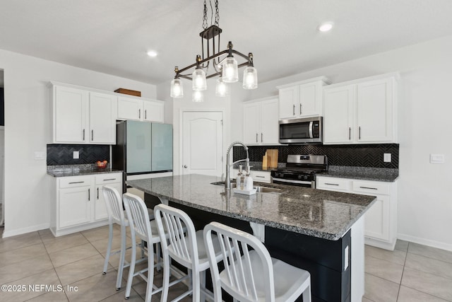 kitchen featuring sink, light tile patterned floors, appliances with stainless steel finishes, a kitchen island with sink, and white cabinets