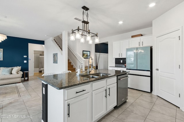 kitchen featuring fridge, sink, a center island with sink, and white cabinets