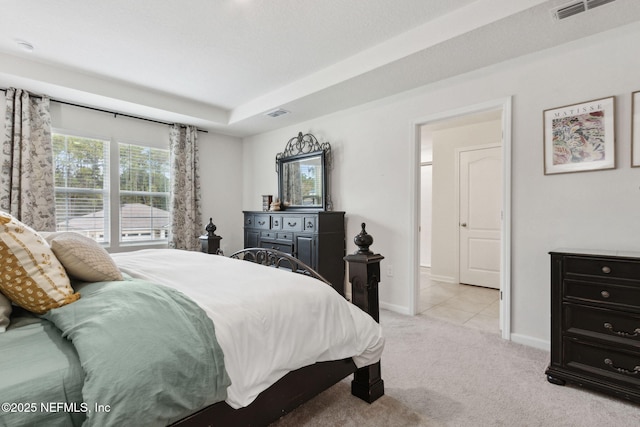 bedroom featuring light colored carpet and a raised ceiling