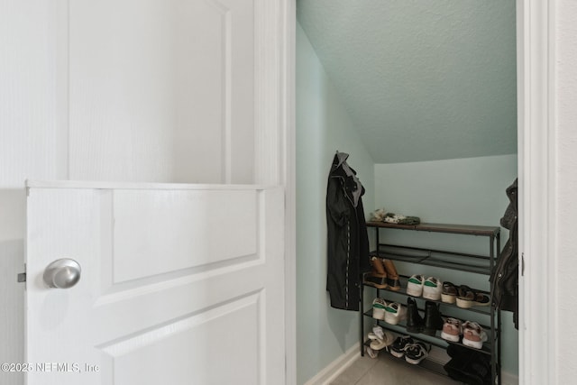 walk in closet with vaulted ceiling and tile patterned floors