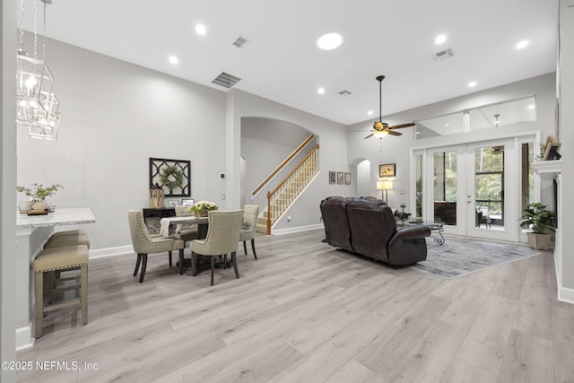 living room featuring ceiling fan with notable chandelier and light hardwood / wood-style floors