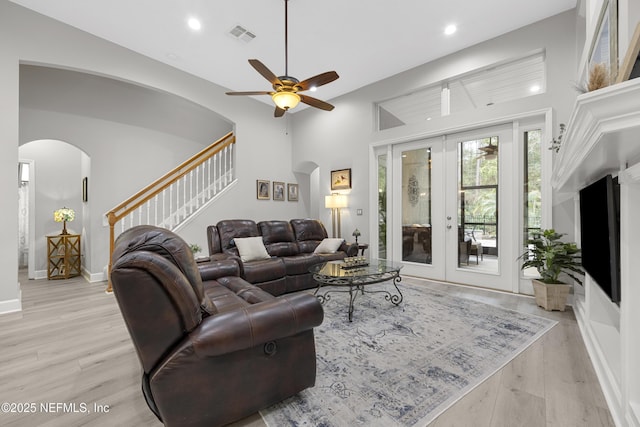 living room with french doors, a high ceiling, ceiling fan, and light hardwood / wood-style flooring