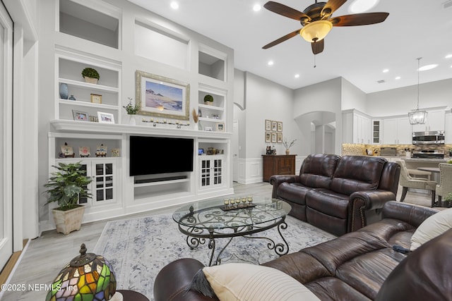 living room with ceiling fan, built in features, and light wood-type flooring