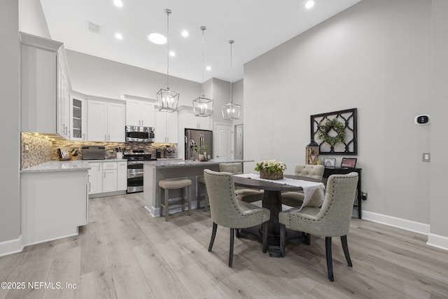 dining room with a towering ceiling and light wood-type flooring