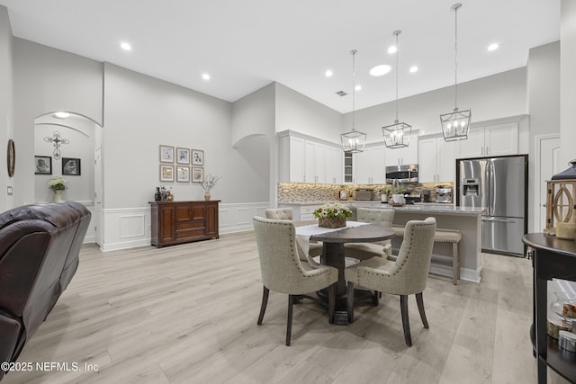 dining area with light wood-type flooring and a high ceiling