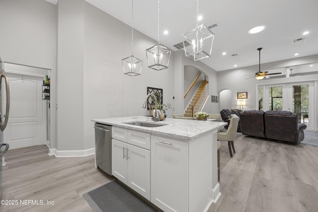 kitchen with sink, white cabinetry, light stone counters, a center island with sink, and stainless steel dishwasher