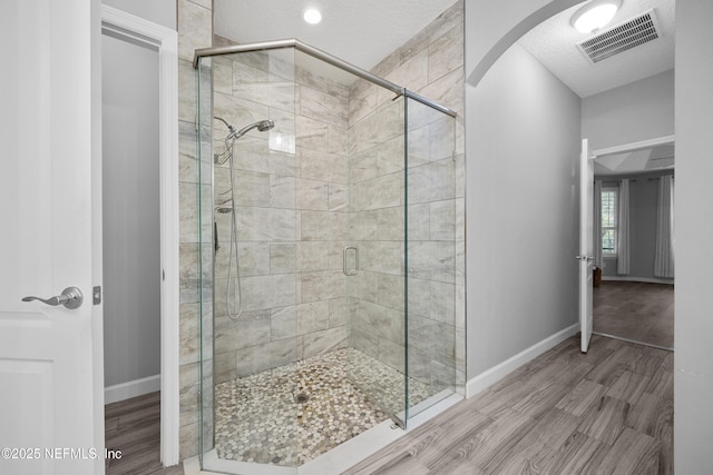 bathroom with hardwood / wood-style flooring, an enclosed shower, and a textured ceiling