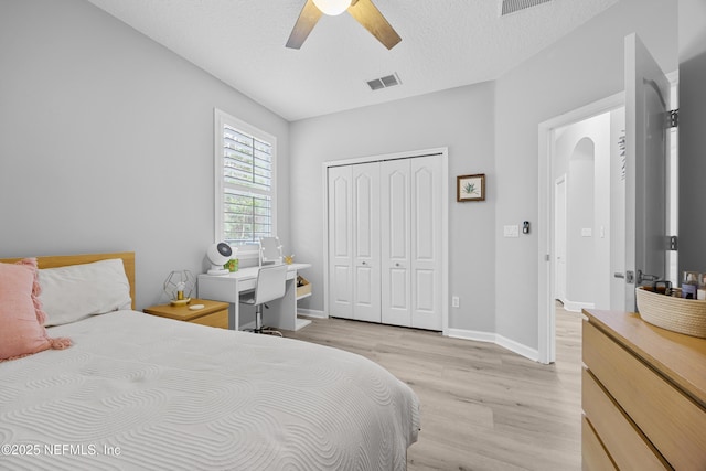 bedroom with ceiling fan, light hardwood / wood-style floors, a closet, and a textured ceiling