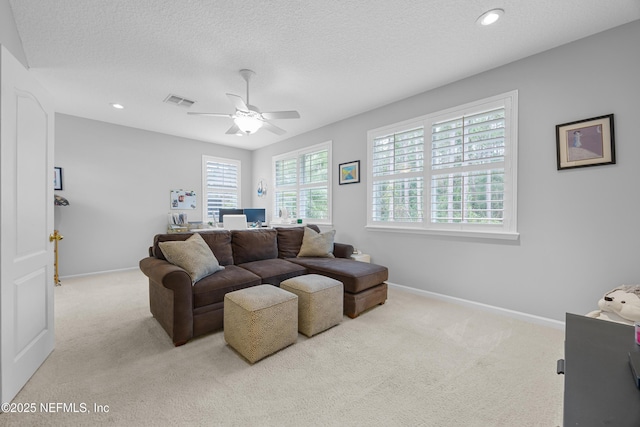 living room featuring ceiling fan, light colored carpet, and a textured ceiling