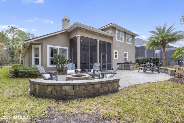 back of house with a yard, a patio area, a sunroom, and an outdoor fire pit