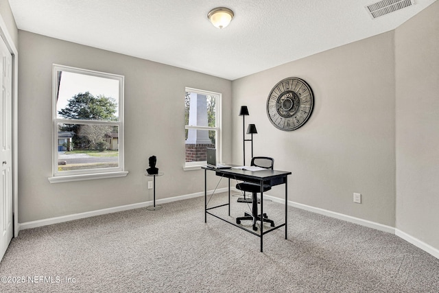 carpeted office featuring a textured ceiling