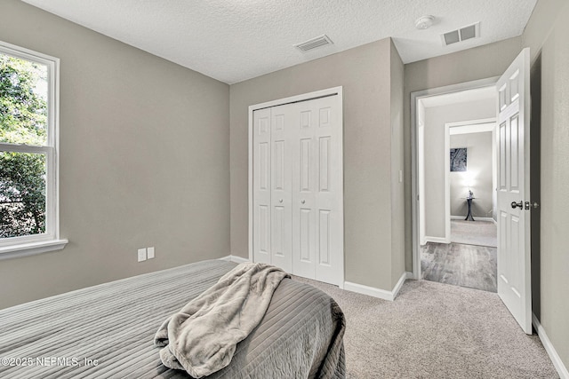 carpeted bedroom featuring a closet and a textured ceiling