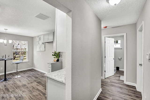 hall featuring dark hardwood / wood-style flooring, a textured ceiling, and a chandelier