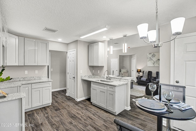 kitchen with hanging light fixtures, white cabinetry, and sink