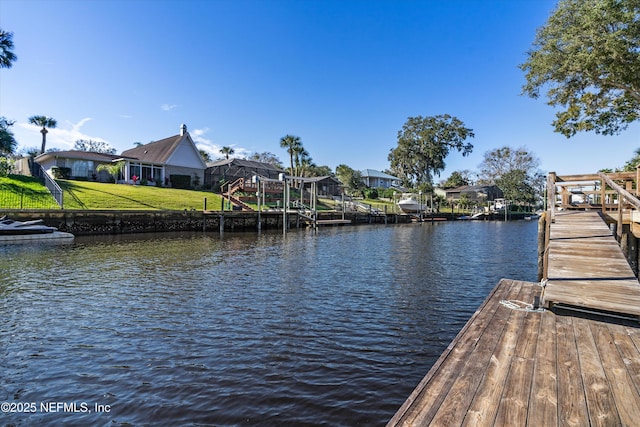 view of dock with a water view and a lawn