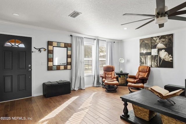 sitting room featuring hardwood / wood-style flooring, ceiling fan, crown molding, and a textured ceiling