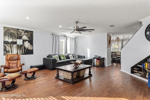 living room featuring wood-type flooring, ceiling fan, a textured ceiling, and crown molding