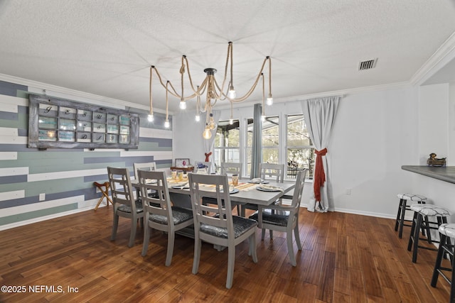 dining area featuring dark wood-type flooring, ornamental molding, a textured ceiling, and a notable chandelier