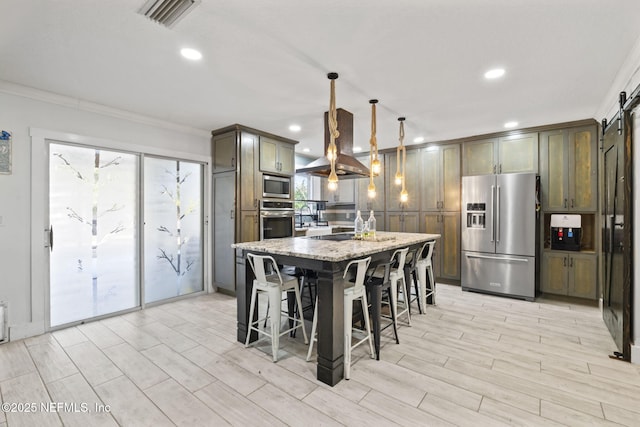 kitchen featuring island range hood, appliances with stainless steel finishes, an island with sink, pendant lighting, and light stone countertops