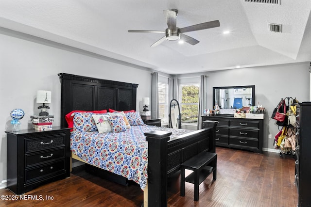 bedroom featuring dark hardwood / wood-style flooring, ceiling fan, a tray ceiling, and a textured ceiling