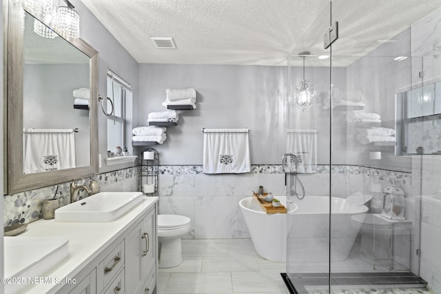 full bathroom featuring toilet, separate shower and tub, a textured ceiling, tile walls, and vanity